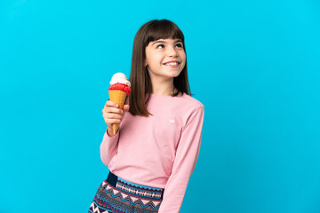 Little girl with a cornet ice cream isolated on blue background thinking an idea while looking up