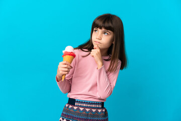 Little girl with a cornet ice cream isolated on blue background and looking up