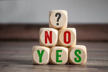 Pyramid made of cubes, dice or blocks with YES, NO and question tag on wooden background