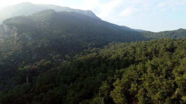 Aerial landscape footage of the hills and mountains with sun rays and some clouds.