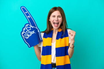 Young sports fan woman isolated on blue background celebrating a victory in winner position