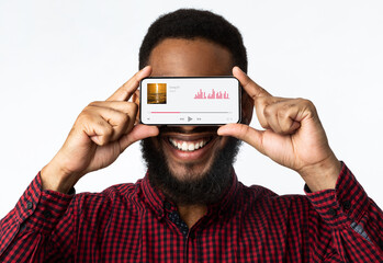 Music Player. Cheerful Black Man Holding Smartphone With Audio Streaming App