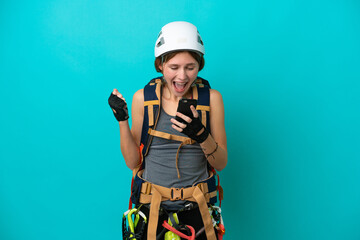 Young English rock climber woman isolated on blue background surprised and sending a message