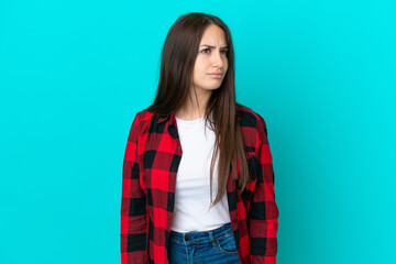 Fototapeta premium Young Ukrainian woman isolated on blue background making doubts gesture looking side