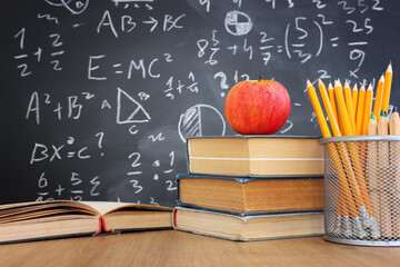 School books on desk infront of blackboard with formulas. education concept