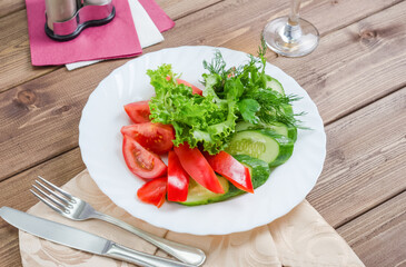Fresh tomatoes with cucumbers, lettuce and dill on a white plate