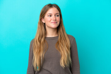 Obraz premium Young blonde woman isolated on blue background having doubts while looking side