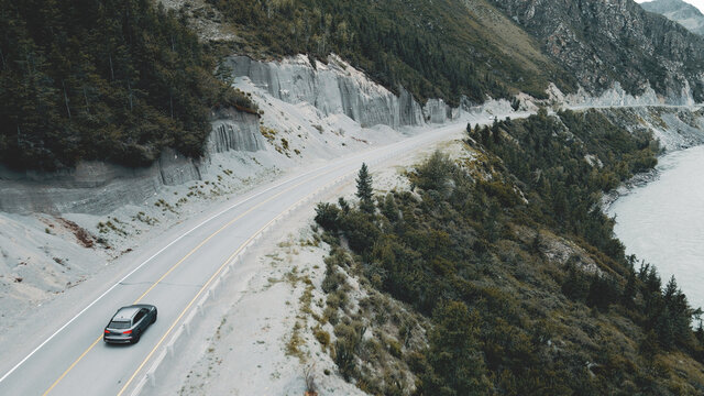 Dark Grey Car Drives Through Narrow Road In The Mountains. Drone Footage