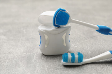 Blue tongue cleaner, toothbrush and dental floss on grey table, closeup - obrazy, fototapety, plakaty