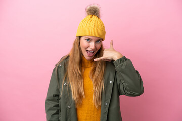Young blonde woman wearing winter jacket isolated on pink background making phone gesture. Call me back sign
