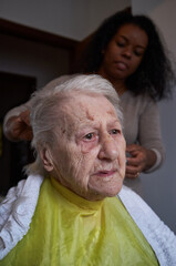 caregiver, cutting her elderly woman hair