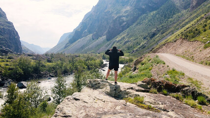 Fototapeta na wymiar A man stay on the edge of a cliff wearing a black anorak. Katu-Yaryk canyon Chulyshman Valley. Altai