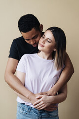 Love, new mixed race parents and family concept - very happy couple, celebrating the news of a pregnancy. Beige background.