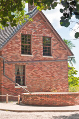 front  view, medium distance of a brick house adjacent to a lighthouse with rain gutters collecting rain and directing it into a brick holding tank