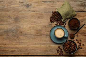 Flat lay composition with coffee grounds and roasted beans on wooden table, space for text