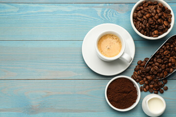 Flat lay composition with coffee grounds and roasted beans on light blue wooden table, space for text