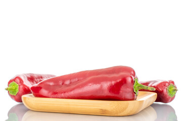 Three red sweet peppers with a wooden tray, close-up, isolated on white.