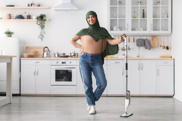 Muslim woman cleaning floor with spray mop and posing
