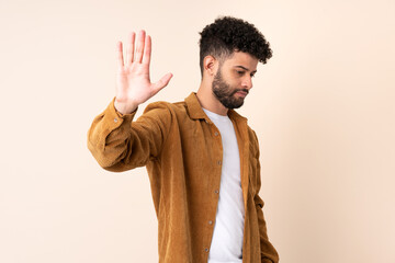 Young Moroccan man isolated on beige background making stop gesture and disappointed