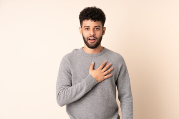 Young Moroccan man isolated on beige background surprised and shocked while looking right