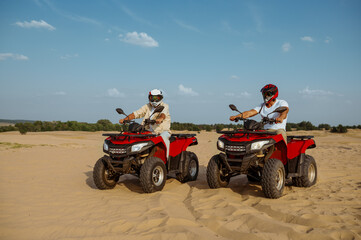 Obraz premium Men in helmets and glasses ride on atv in desert