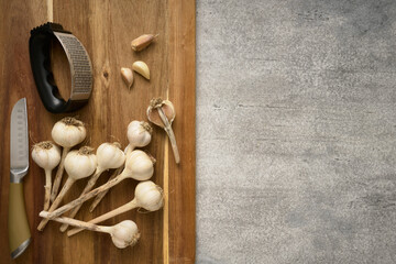 Fototapeta na wymiar Wooden cutting board with garlic heads and garlic press, close up
