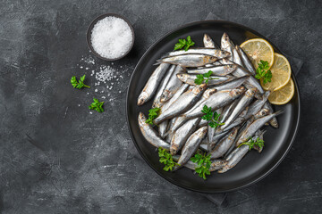 Salted fish with lemon and parsley on a dark background with space to copy.