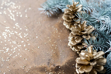 natural golden cones on a wooden table with gold spangles in the shape of stars, among fir branches