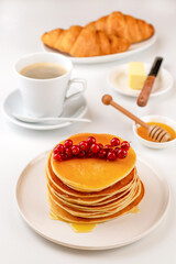 Pancakes for breakfast with honey and coffee, buttered croissants.