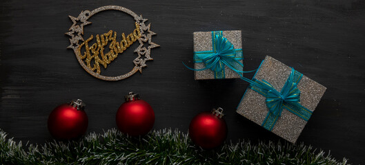 Christmas background- with gold sign, red spheres and silver gifts with blue bow on black background