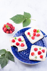 Toast with cream cheese and fresh raspberries on a blue plate. A delicious summer dish for breakfast. Close-up.