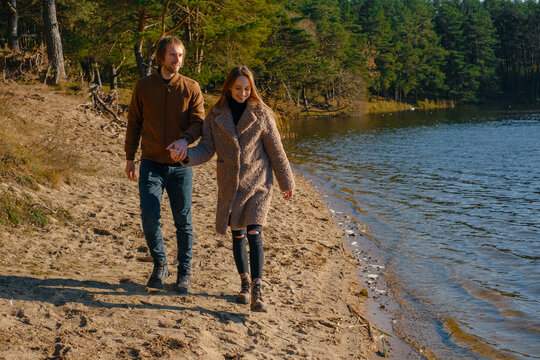 Romantic couple walking on sandy lakeside