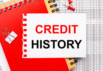 Against the background of the reports, there are red and brown notepads, a white paper clip, red buttons and a white sheet of paper with the text CREDIT HISTORY. Business concept