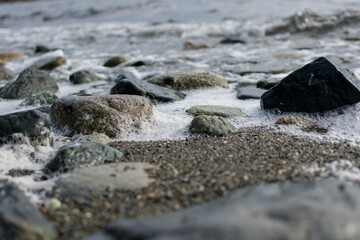 Sea foam near rocks on the beach at the Pacific Northwest Gulf Islands in British Columbia, Canada