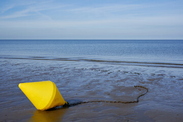 Yellow buoy on the beach of the North Sea. This sea sign marks the area for swimmers and bathers....