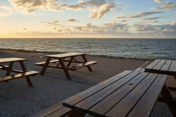 Fototapeta na wymiar 4 benches on an asphalt dam in south holland in front of the north sea. Seating for travelers. Just before sunset in Netherlands, Zeeland, Brouwersdam.