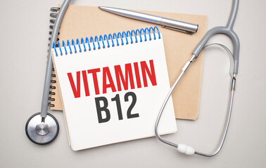White notepad with the words vitamin b12 and a stethoscope on a blue background. Medical concept