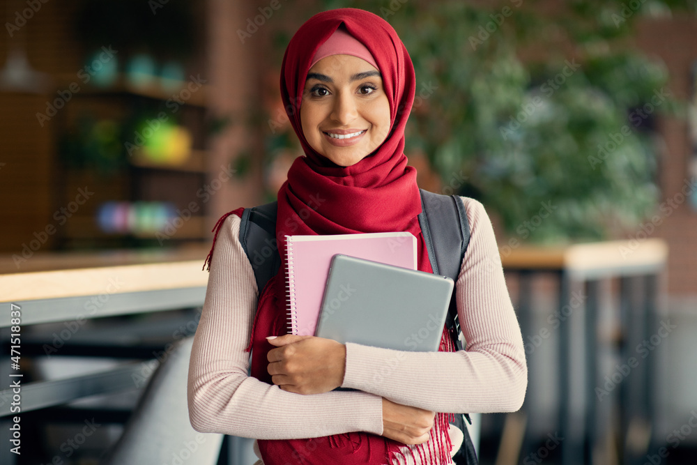 Wall mural Happy muslim woman student with backpack and books at cafe