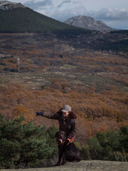 Fototapeta na wymiar Female with her one year and seven months old chocolate labrador and valley of oaks in autumn in the background.