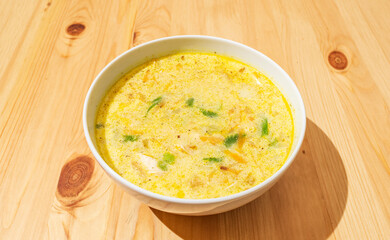 Homemade creamy nettle soup in a deep white plate on a wooden background