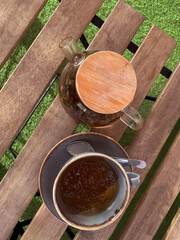 Glass teapot with a cup of tea on a wooden table top view