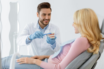 Fototapeta premium Dentist holding jaw and tooth brush, having conversation with patient