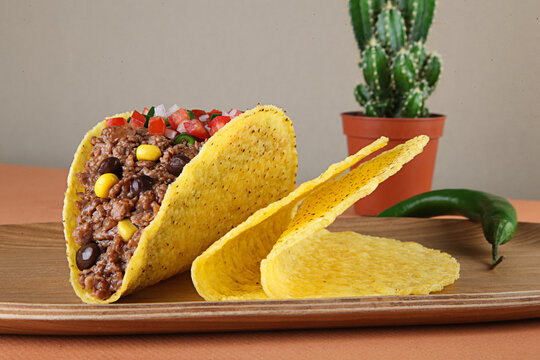 Mince meat tacos with corn and sauce on wooden tray