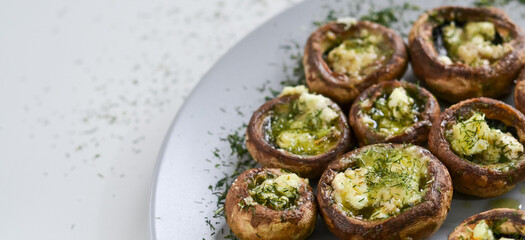 A dish full of mushrooms stuffed with butter, cheese and spices on a wooden kitchen table
