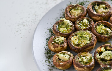 A dish full of mushrooms stuffed with butter, cheese and spices on a wooden kitchen table