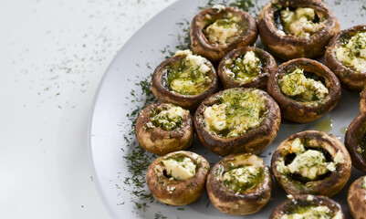 A dish full of mushrooms stuffed with butter, cheese and spices on a wooden kitchen table