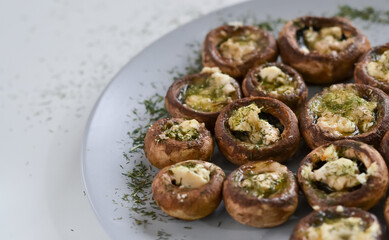 A dish full of mushrooms stuffed with butter, cheese and spices on a wooden kitchen table