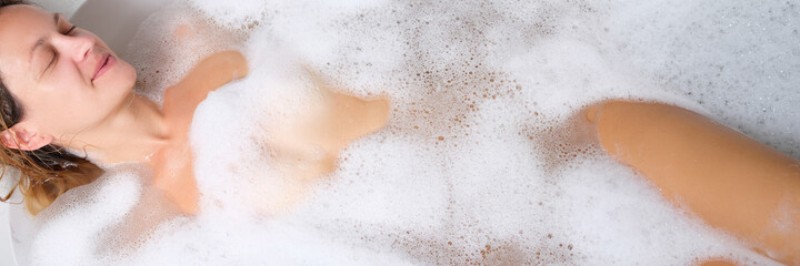 Young nude woman lying in bubble bath
