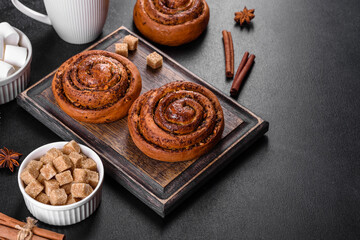 Freshly baked cinnamon roll with spices and cocoa filling on a black background