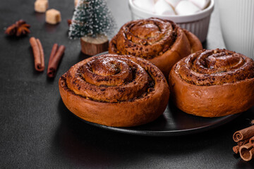 Freshly baked cinnamon roll with spices and cocoa filling on a black background